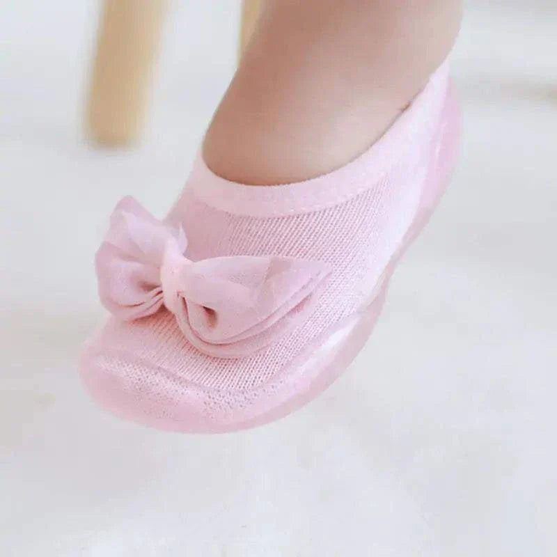 Pink toddler shoes with anti-slip sole and built-in cozy socks, featuring a decorative bow for style and comfort.