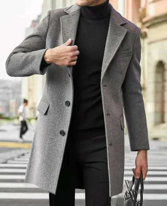 Men's long sleeved woolen coat in grey, classic design with button closure and notch lapel, worn by a model outdoors.