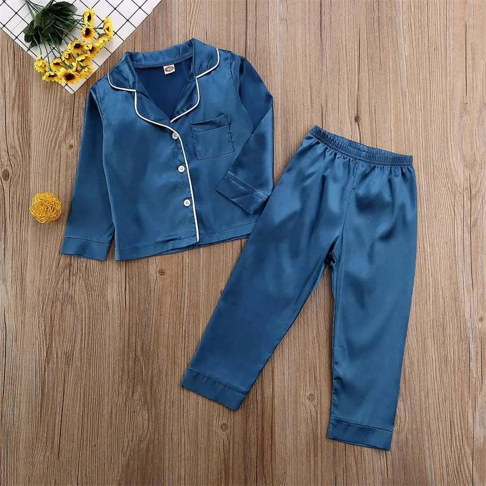 Luxurious blue silk satin toddler pajamas set on wooden floor.