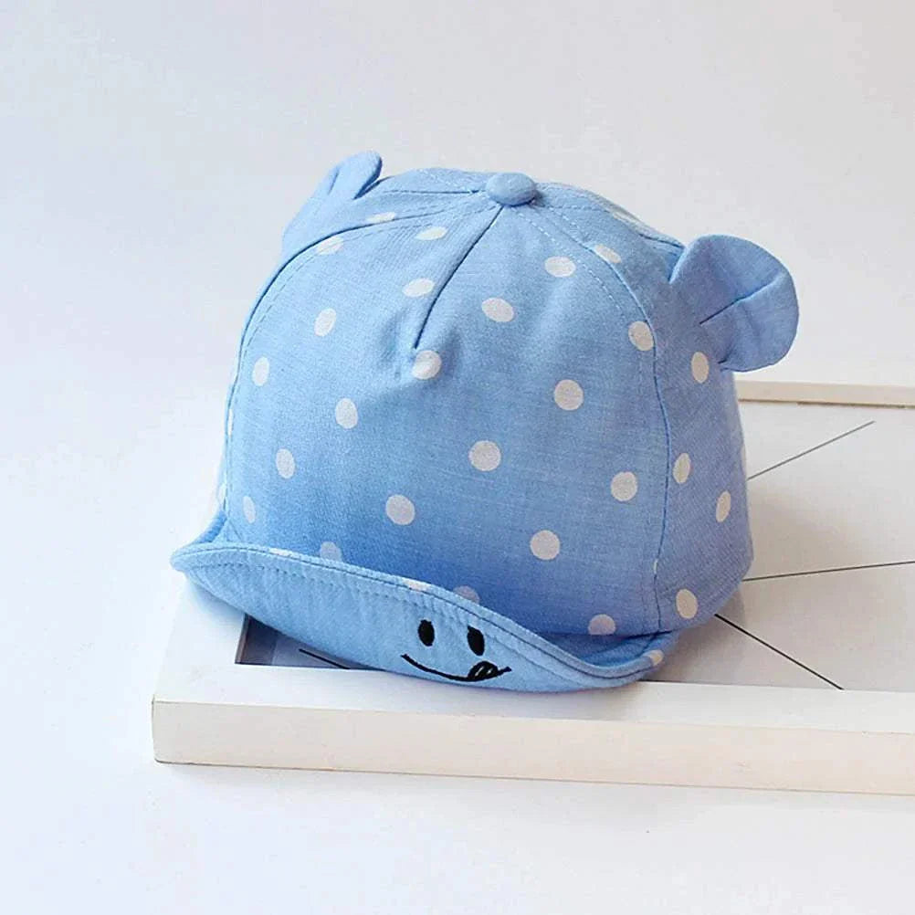 Toddler sun hat with cute dots and ear coverage on blue fabric.