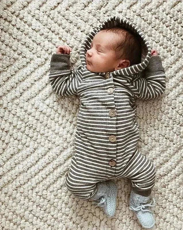 Baby sleeping in a striped hooded romper on a textured blanket.