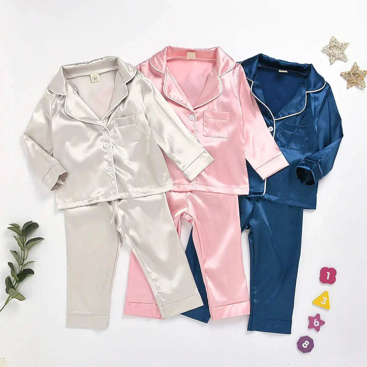 Toddler pajamas in silk satin featuring vibrant colors of gray, pink, and dark blue.